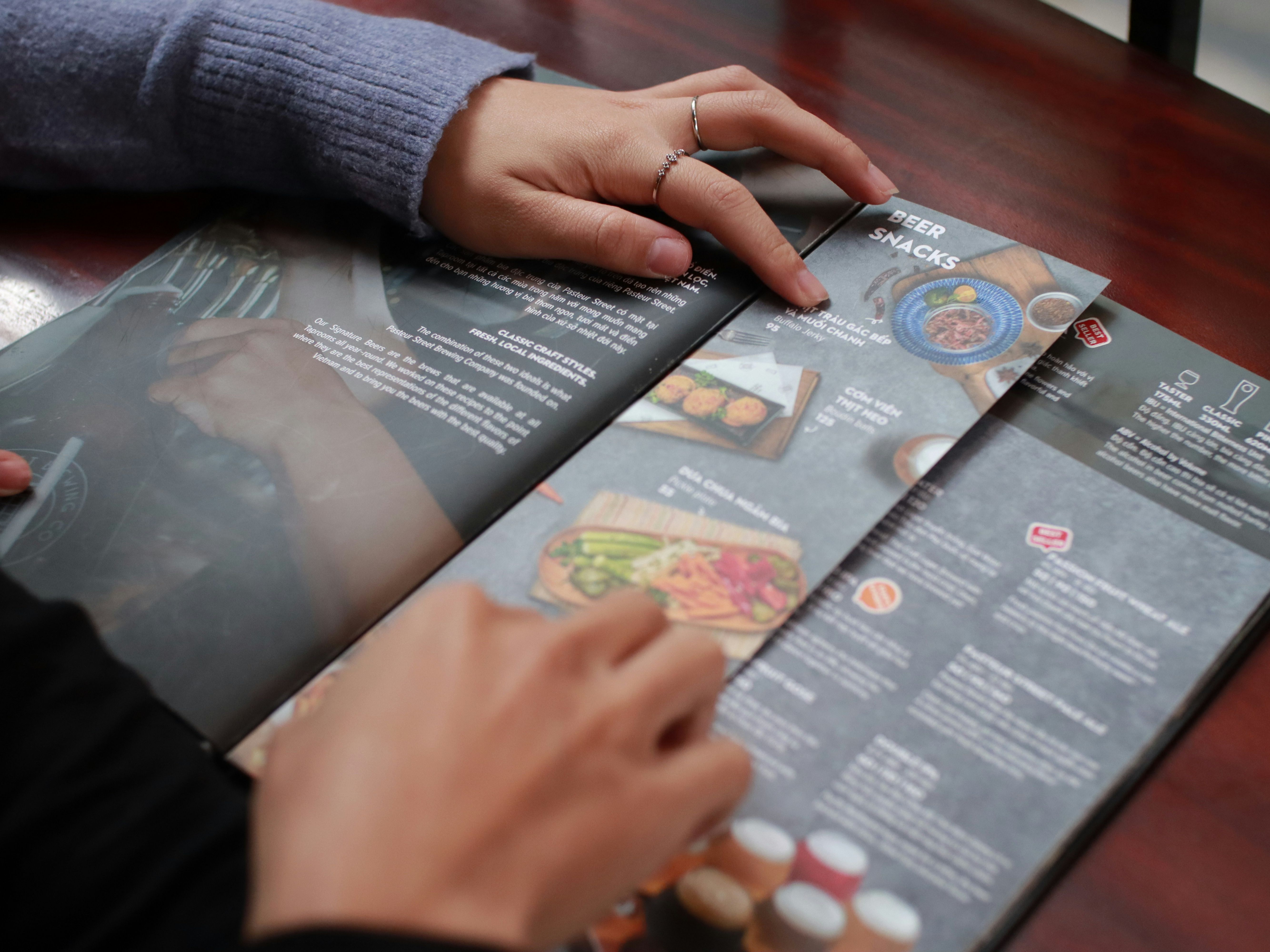 Two people looking at a food and drink menu at a restaurant table