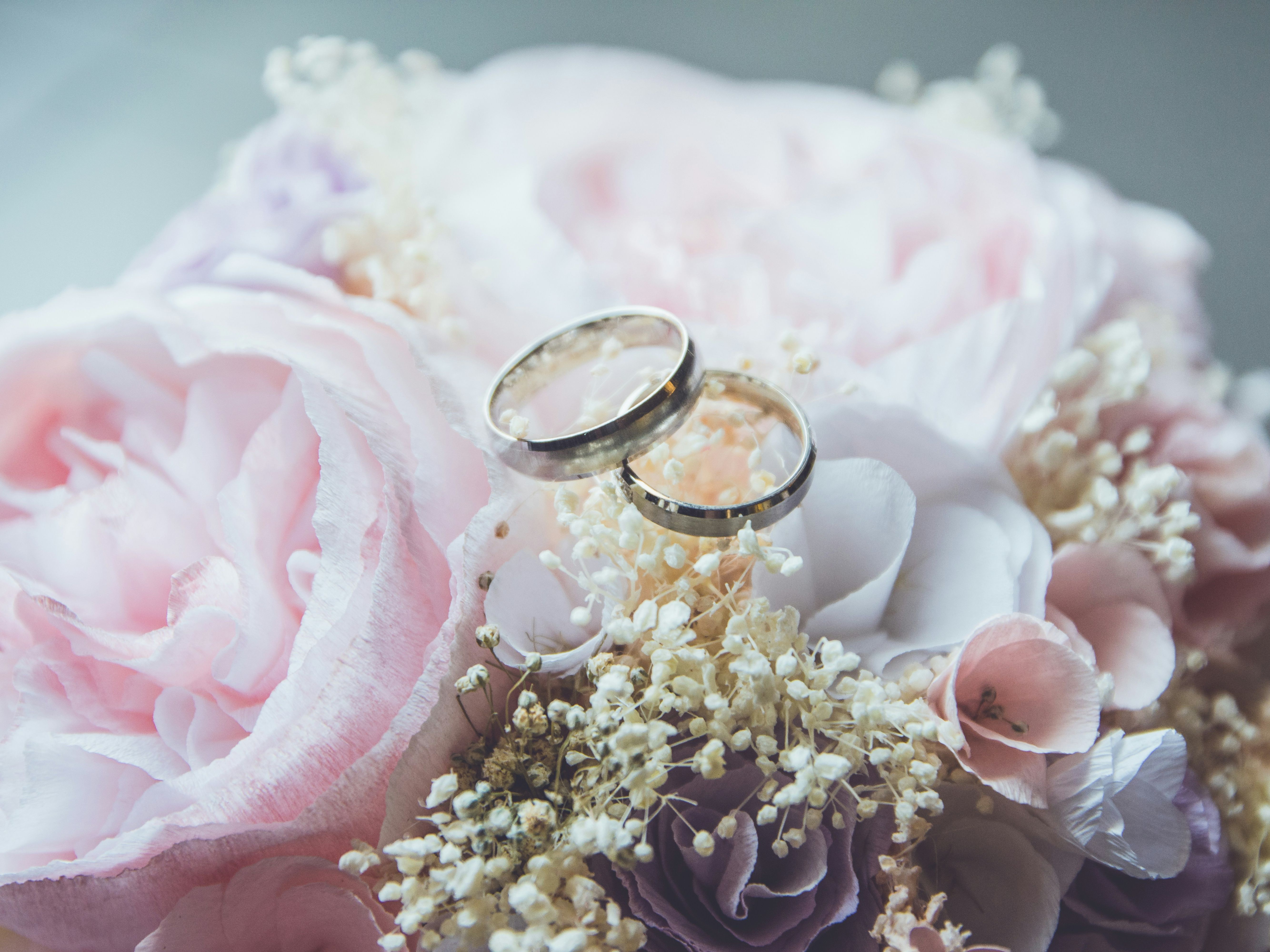 Two wedding rings resting on a bouquet of pink and white flowers