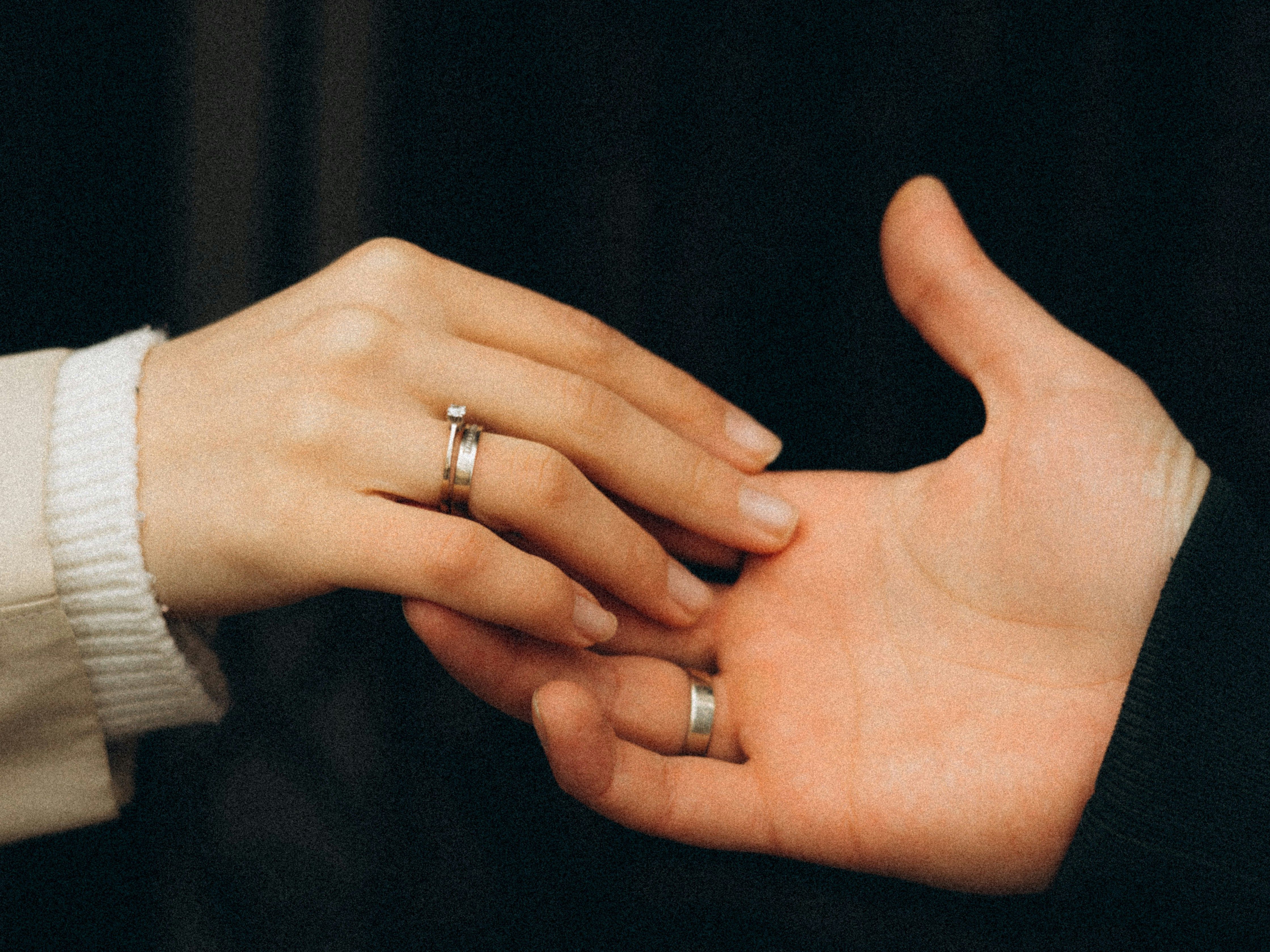 Two hands gently touching, both wearing rings