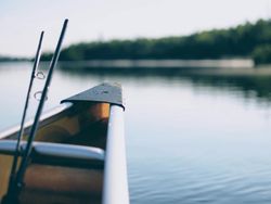 Close-up of a canoe with fishing rods on a calm lake