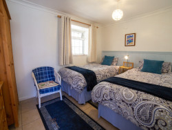 Twin room with blue blanket and cushions, and chair in room