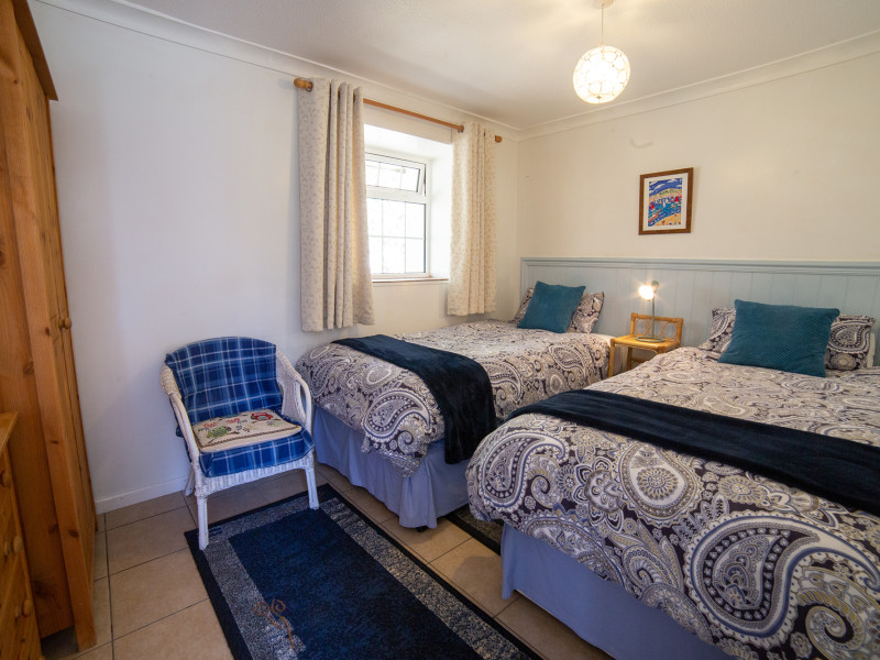 Twin room with blue blanket and cushions, and chair in room