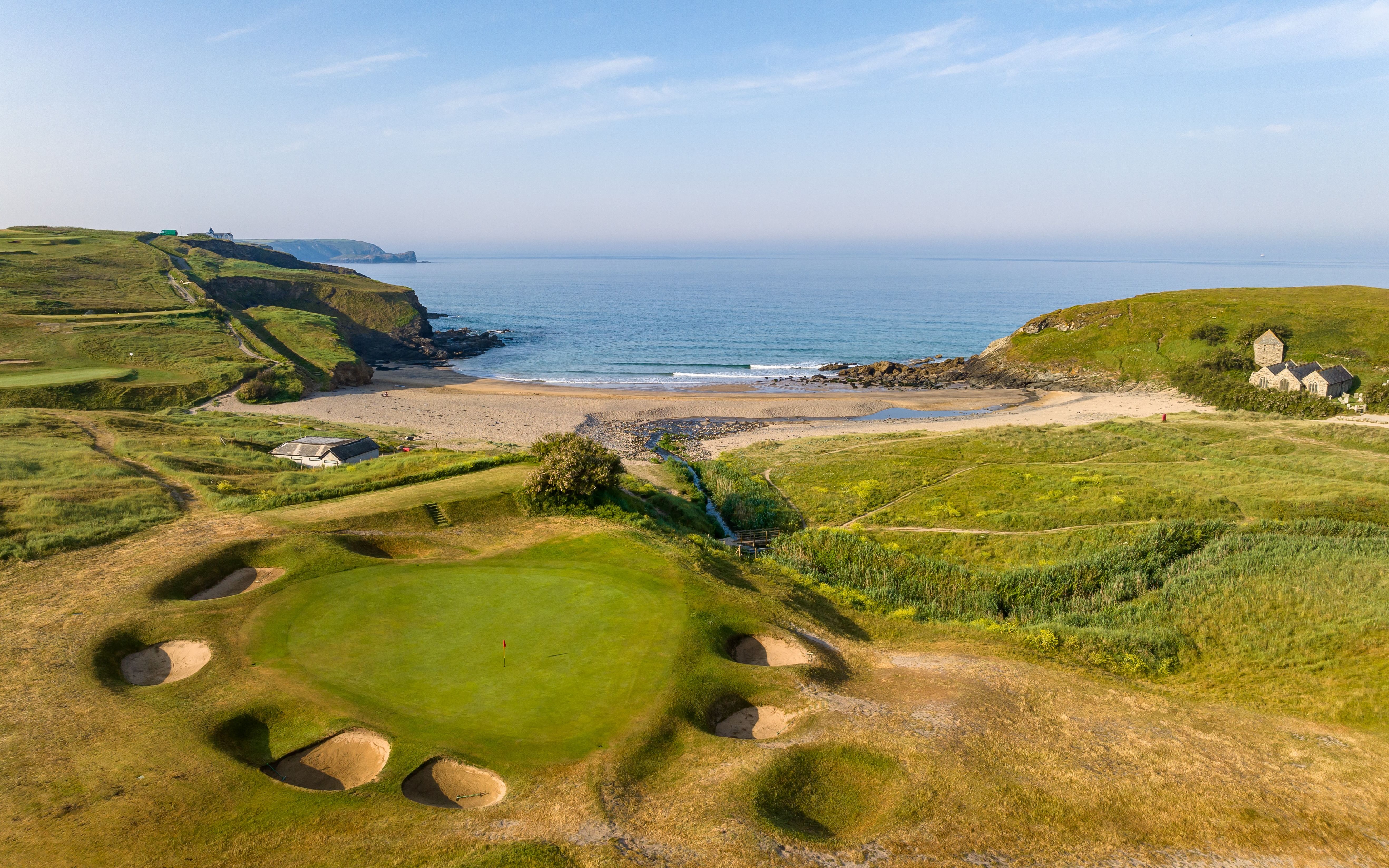A panoramic shot of Mullion Golf Club's golf course, highlighting its pristine greens and picturesque landscape.