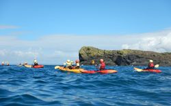 A team of kayakers enjoying the ocean, representing one of the six activities offered by Lizard Adventure.