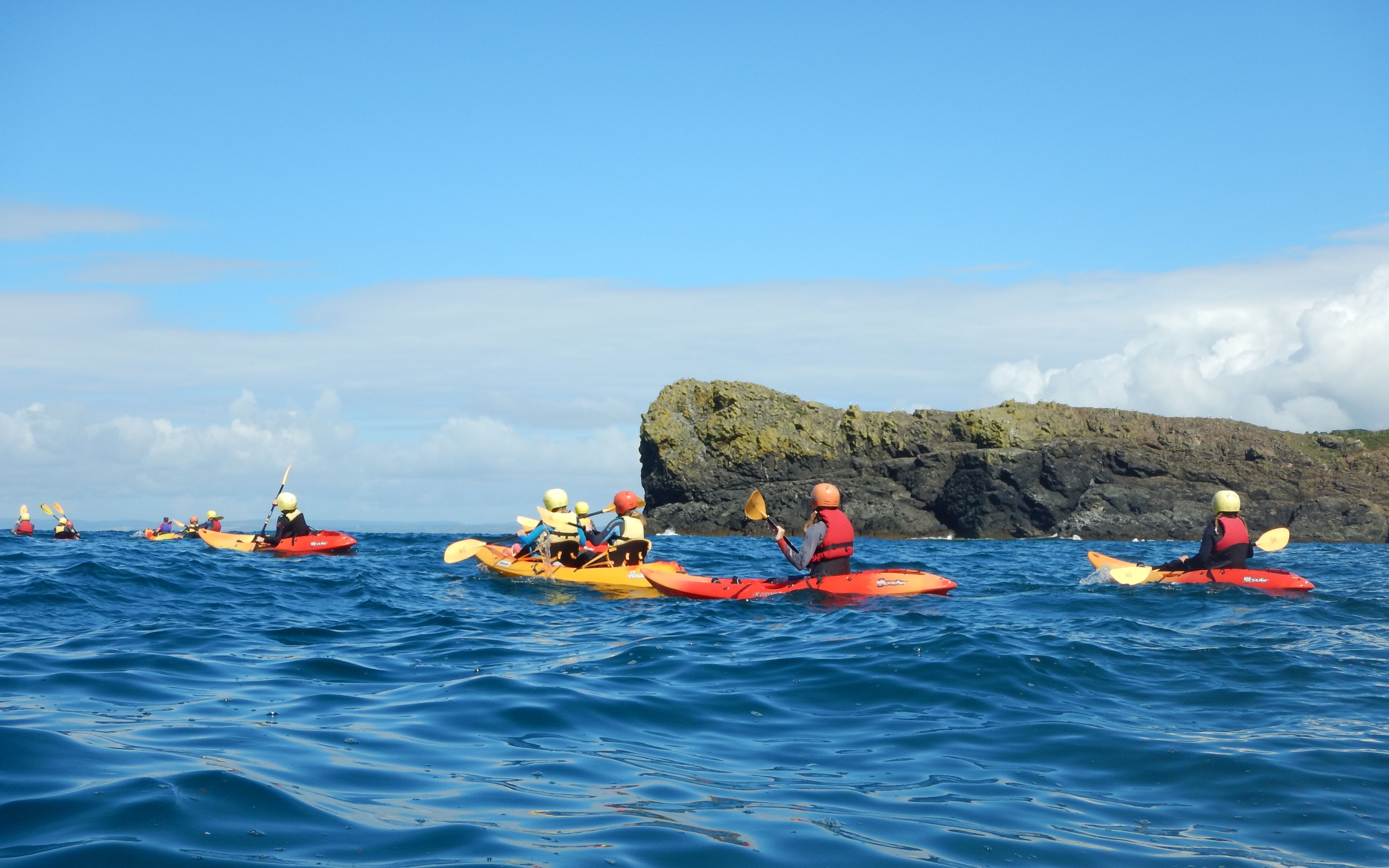 A team of kayakers enjoying the ocean, representing one of the six activities offered by Lizard Adventure.