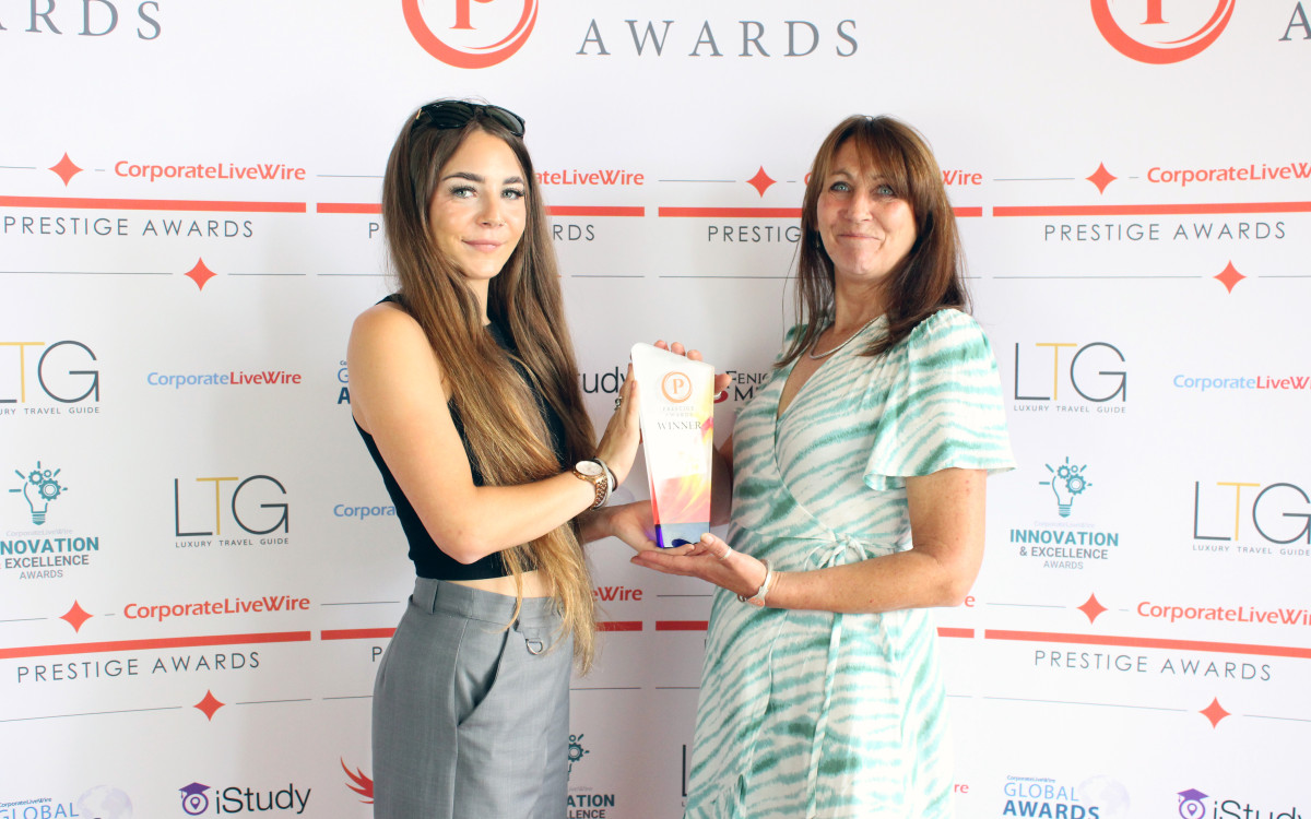 Two women proudly display their award at the Prestige Awards event, standing together.
