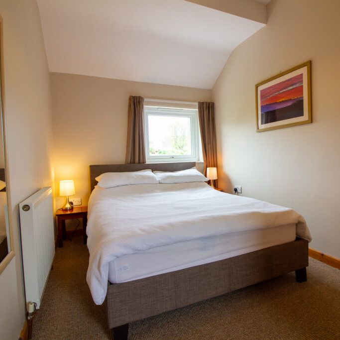 Cozy bedroom with a double bed, lamps, and a window