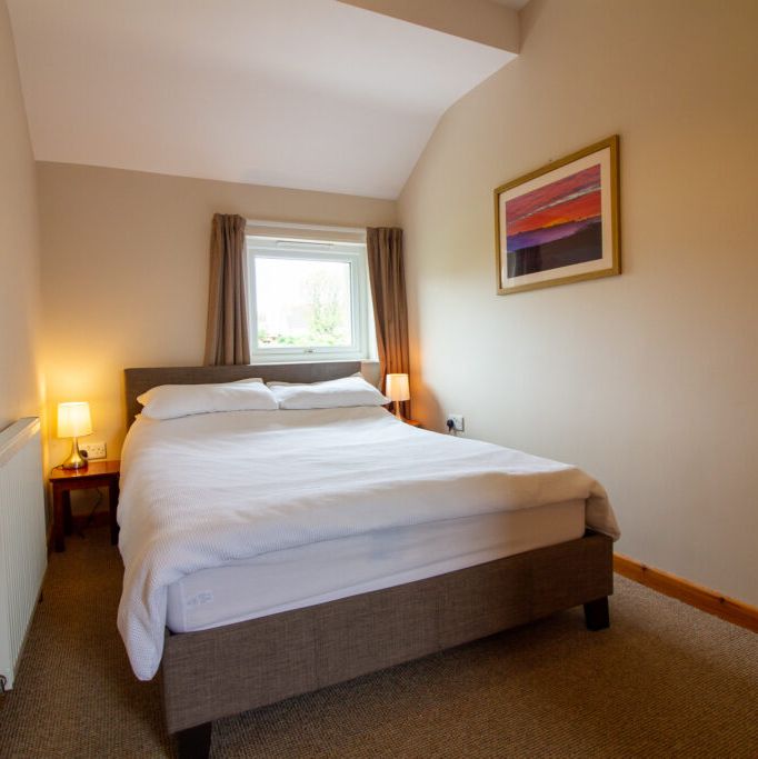 Cozy bedroom with a double bed, lamps, and a window