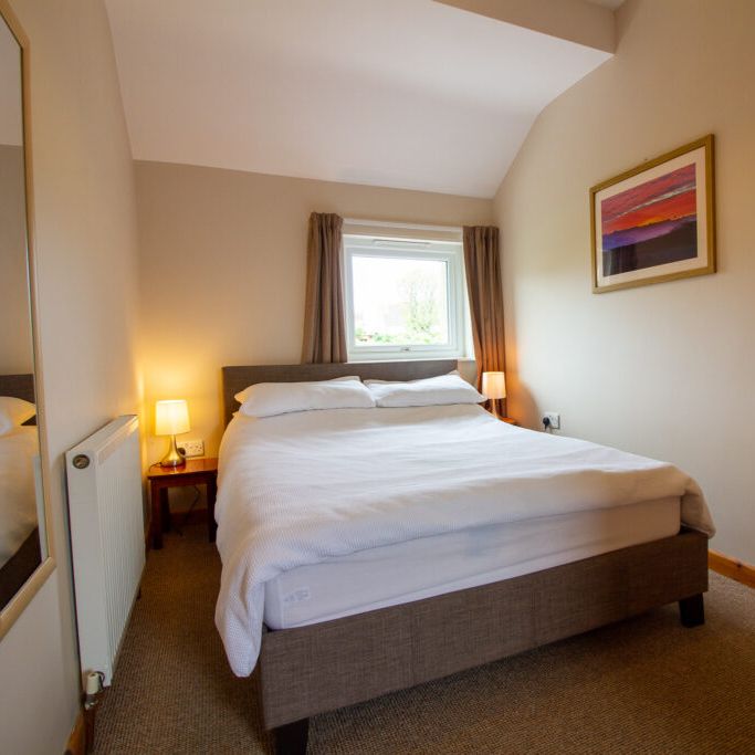 Cozy bedroom with a double bed, lamps, and a window