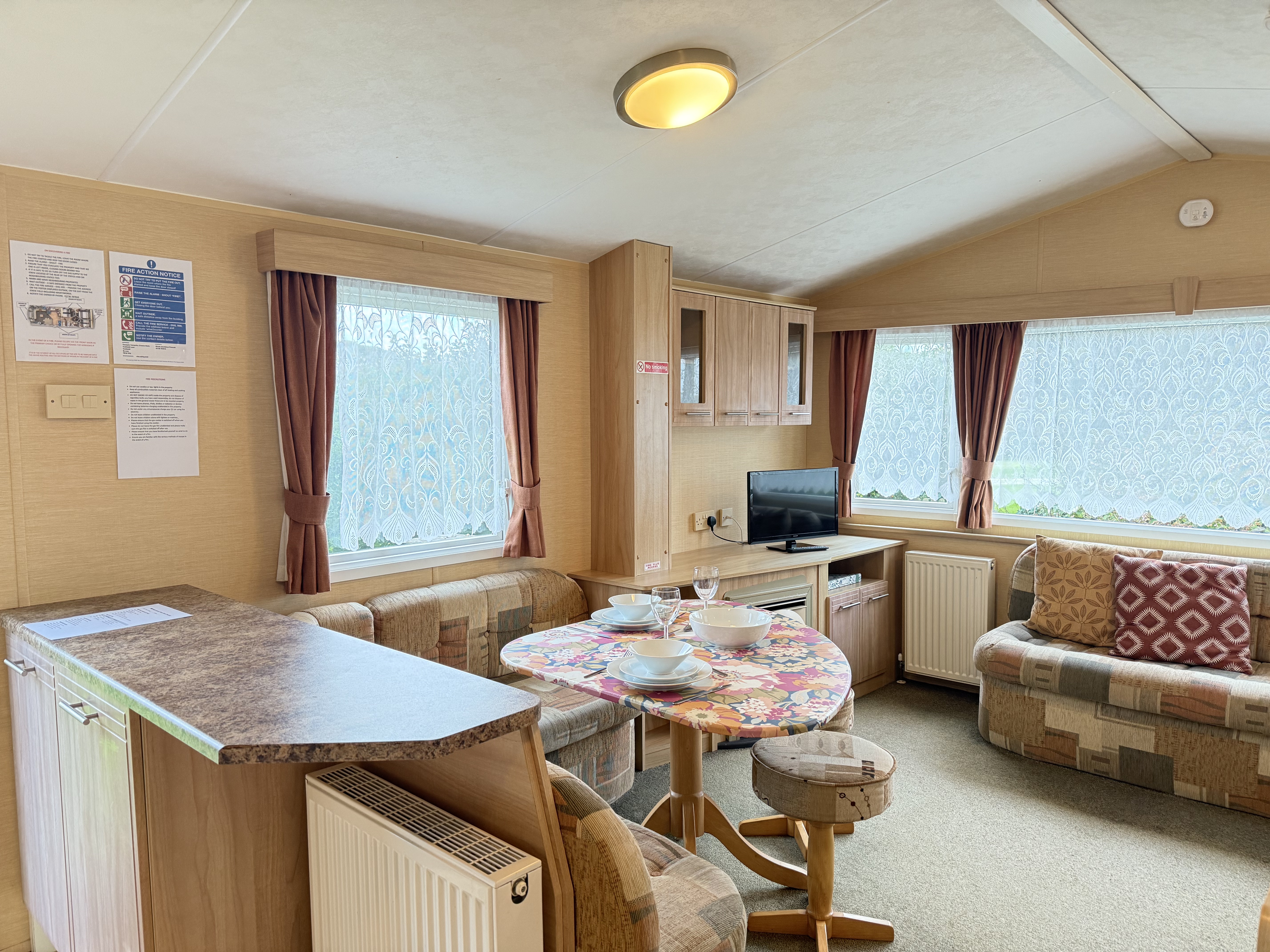 Interior of a cozy caravan living area with a small dining table, television, and sofas.