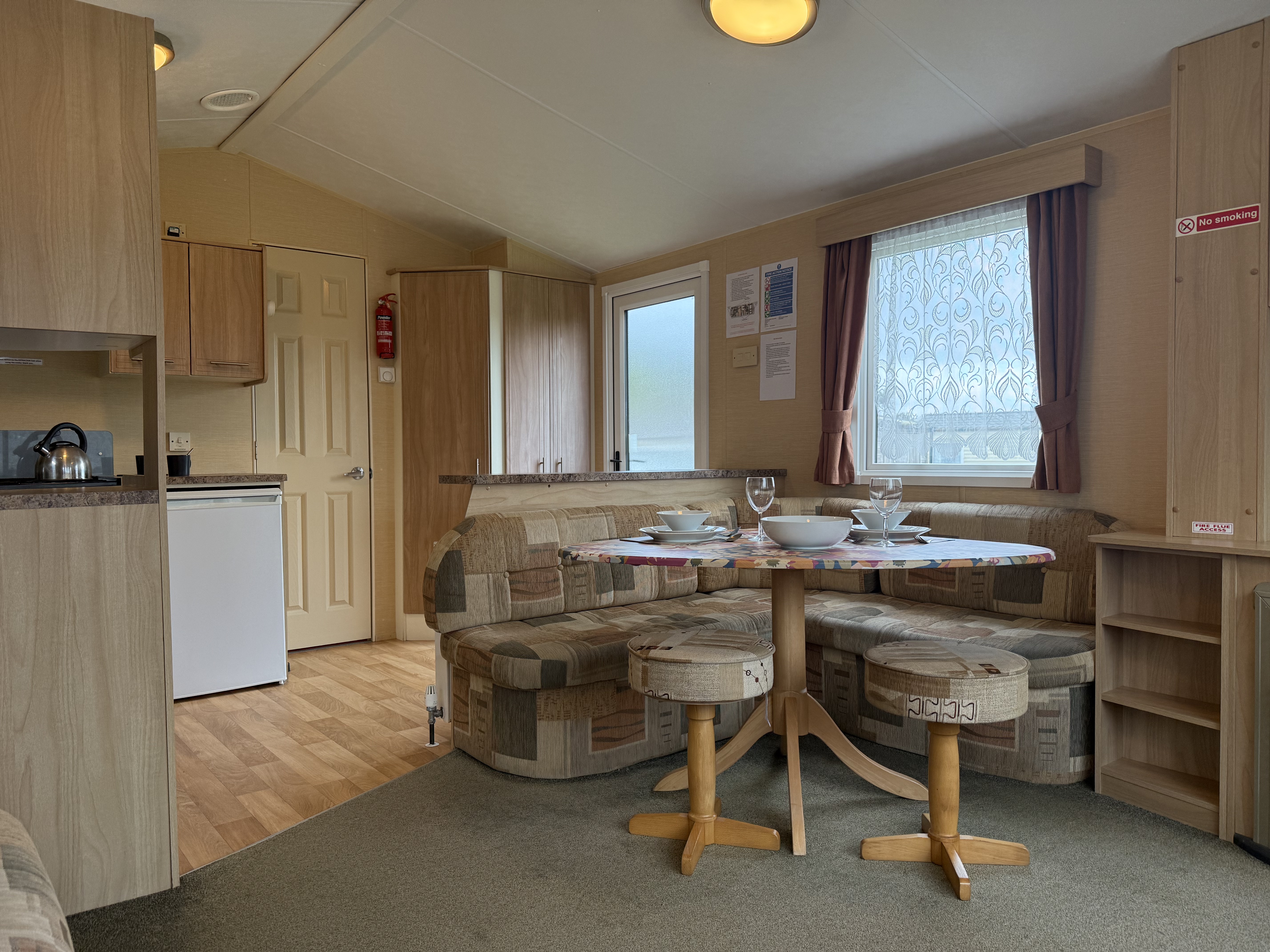 Interior of a cozy mobile home with a small dining area, kitchenette, and seating.