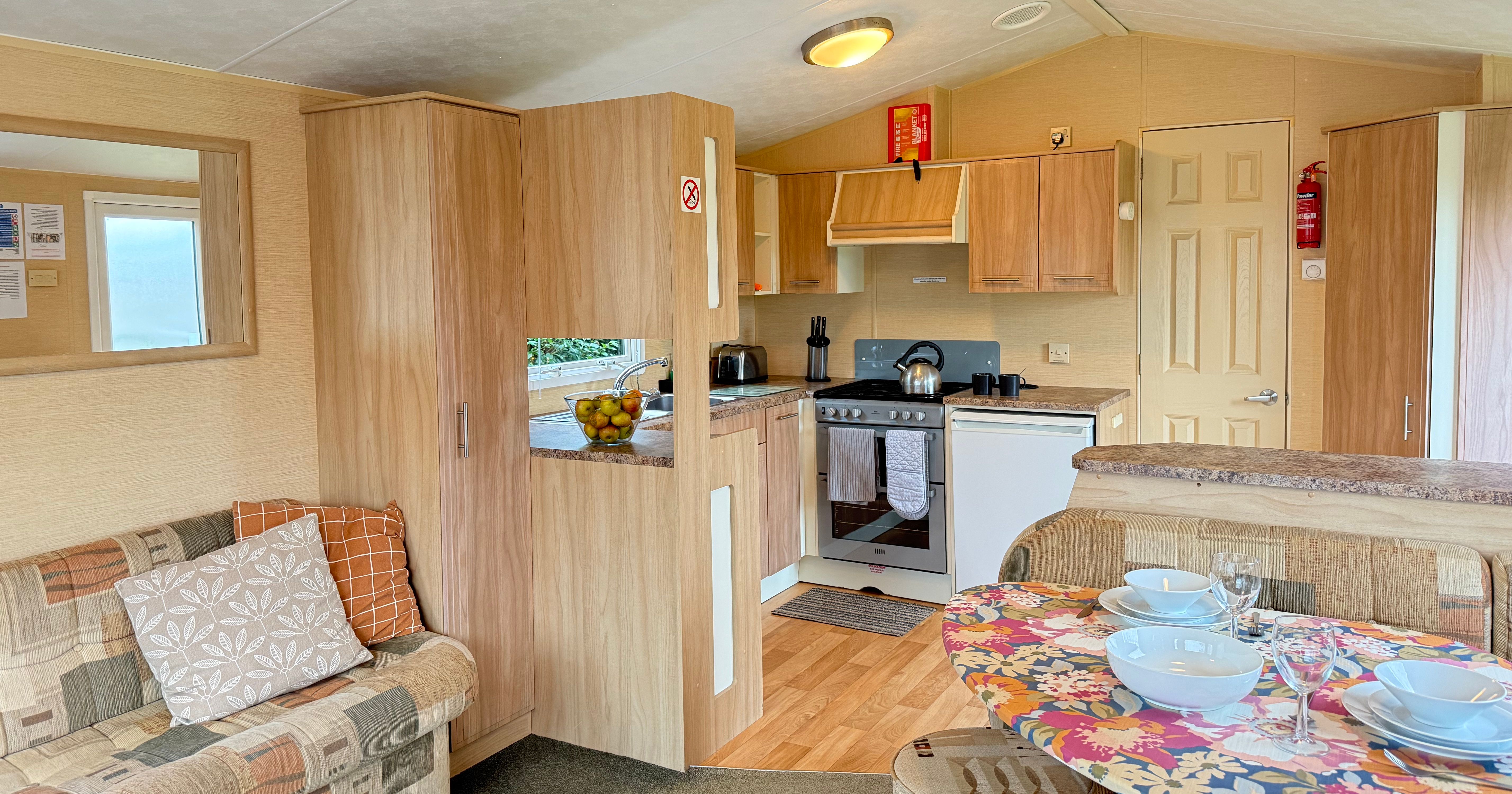 Interior of a cozy mobile home with kitchen, sofa, and dining area