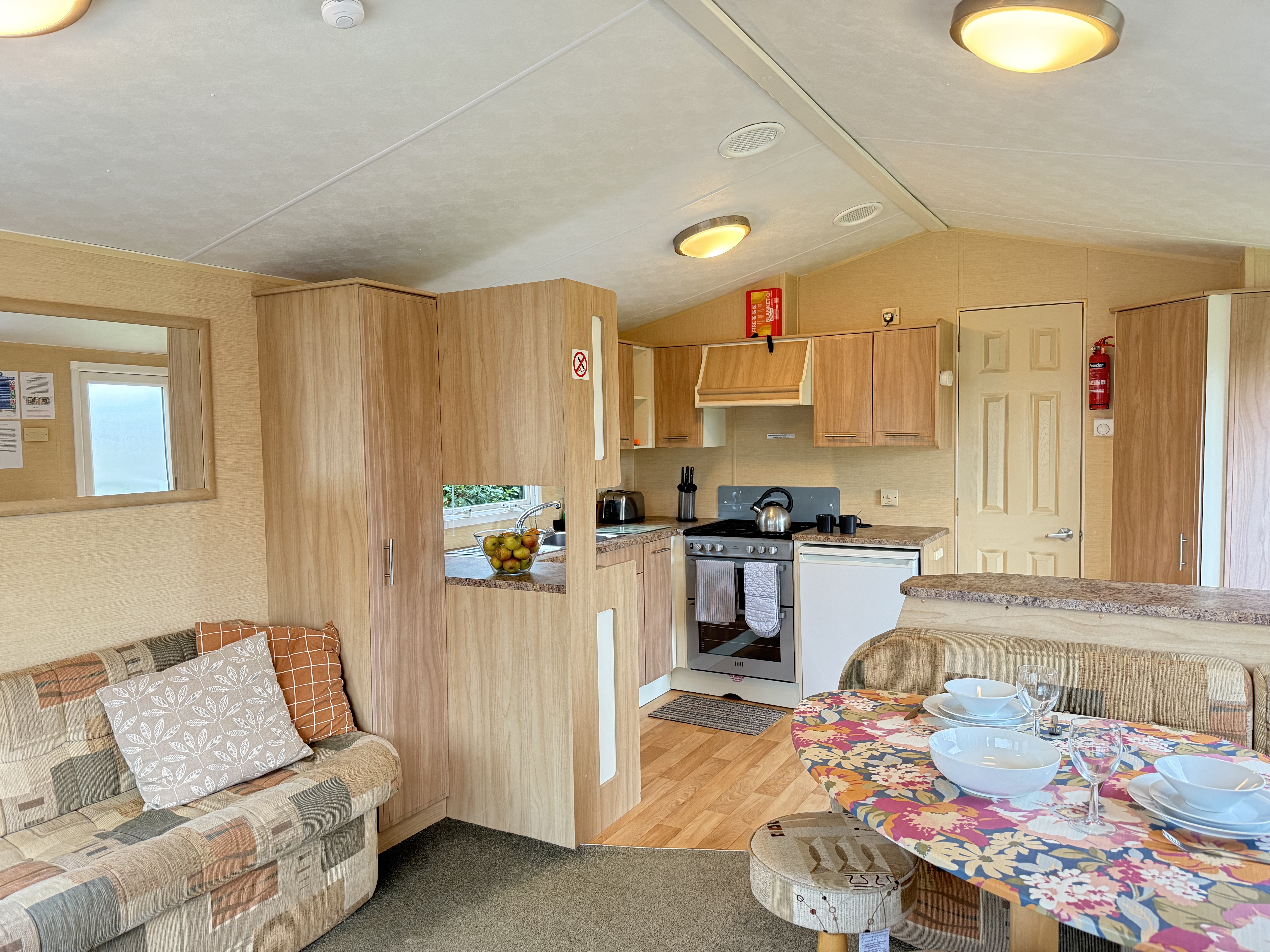 Interior of a cozy mobile home with kitchen, sofa, and dining area