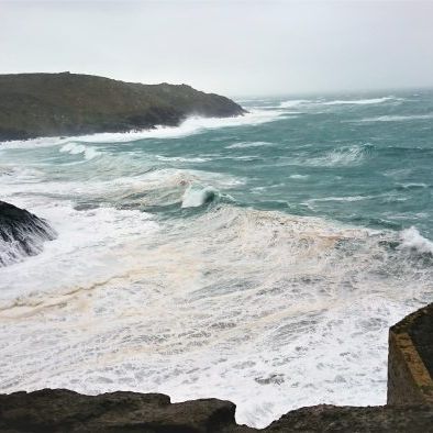 View of rough ocean waves and rocky coastline seen through an old stone window frame
