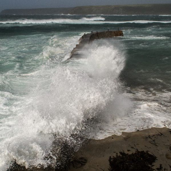 Powerful waves crashing over a pier during a stormy sea at Sennen Cove.