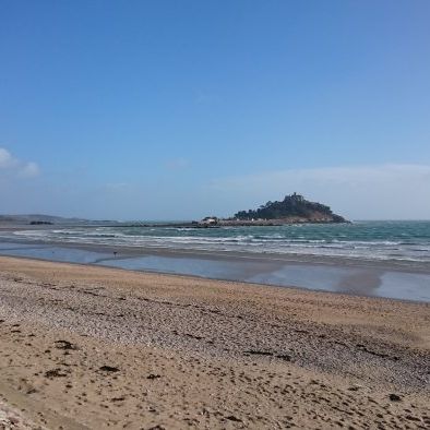 View of St Michael's Mount from a sandy beach under a clear blue sky