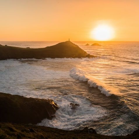 Sunset over Cape Cornwall with waves crashing against the coastline