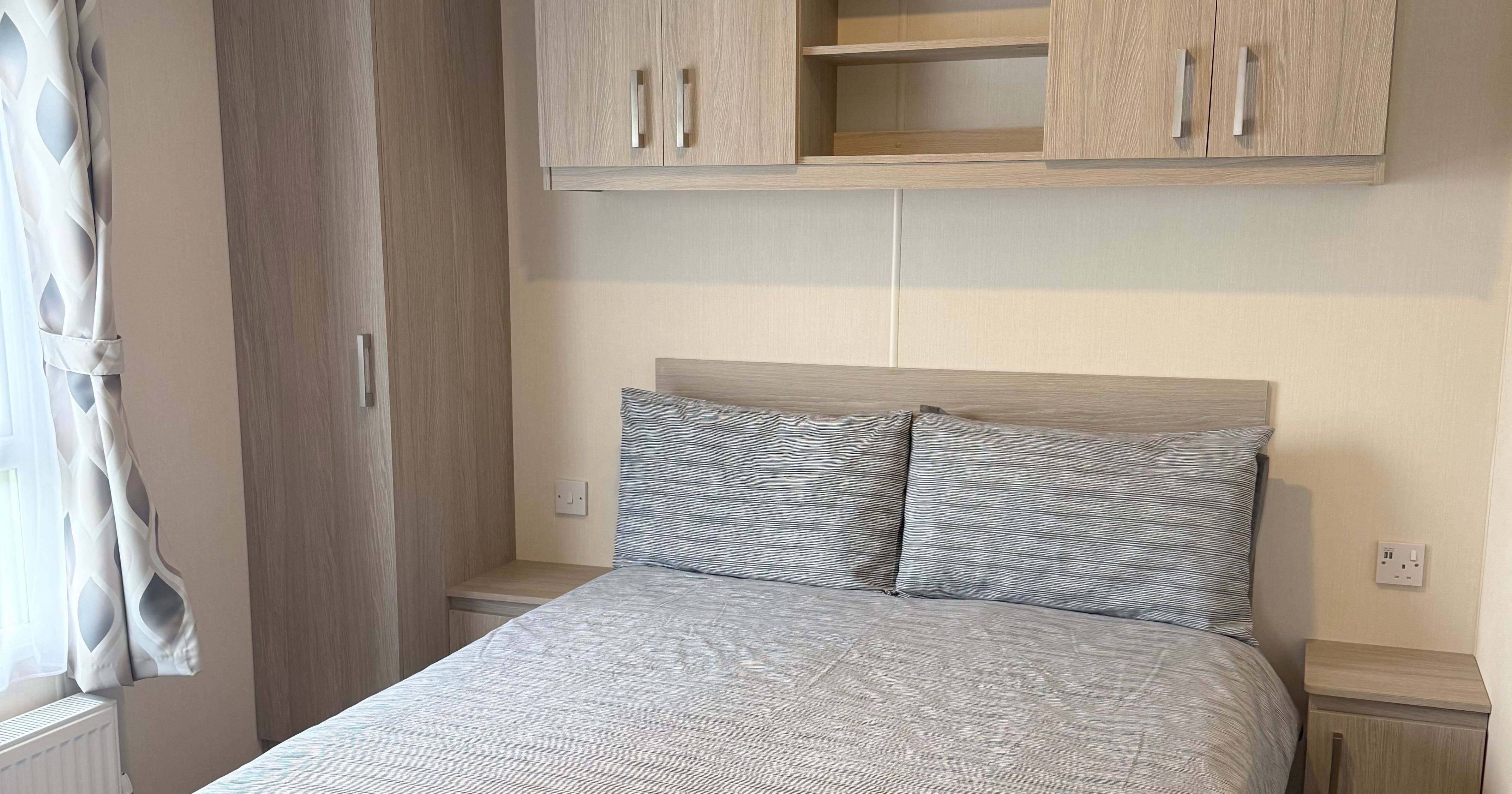 Modern bedroom with double bed, wooden wardrobes, and overhead cabinets