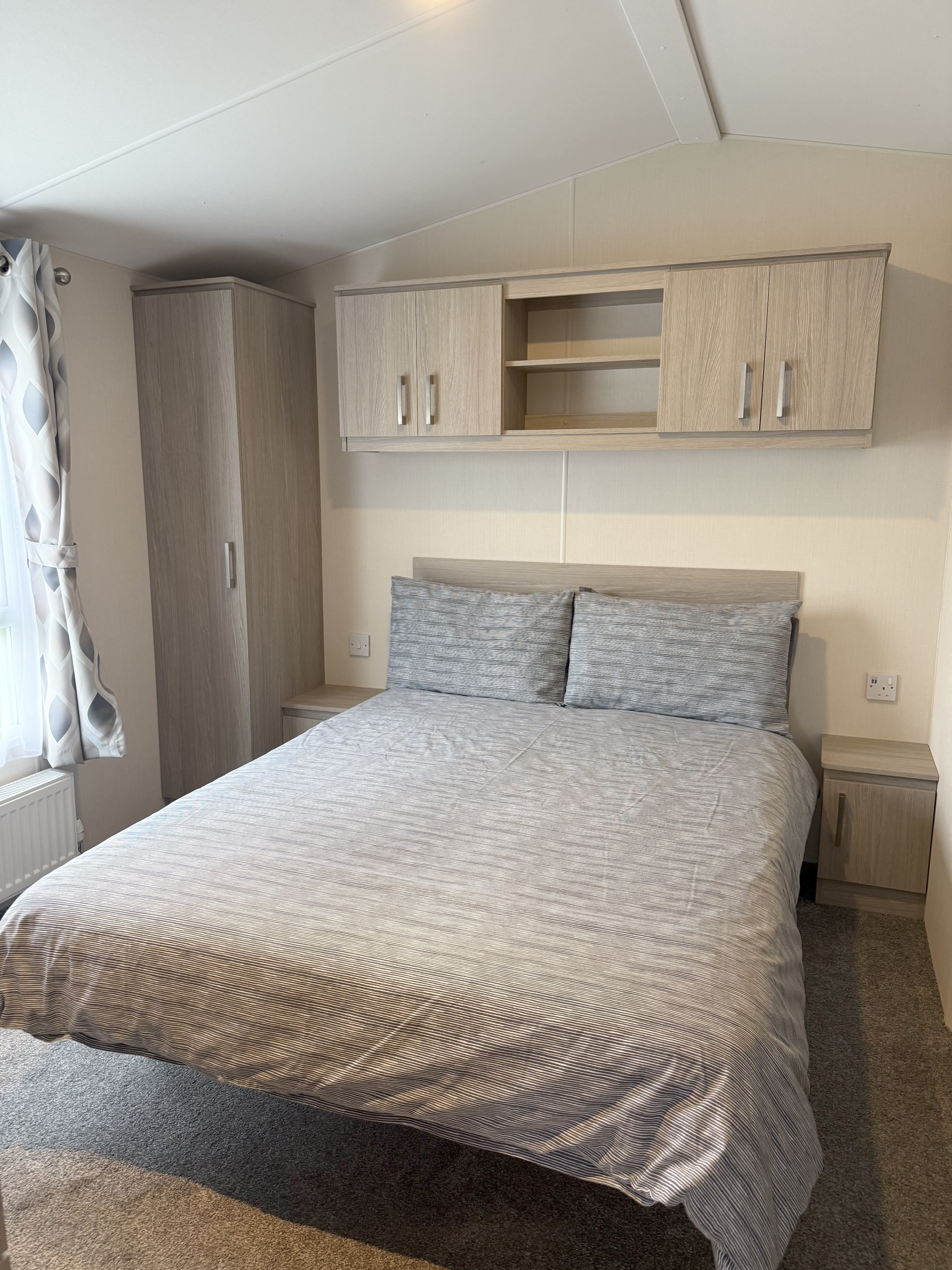 Modern bedroom with double bed, wooden wardrobes, and overhead cabinets