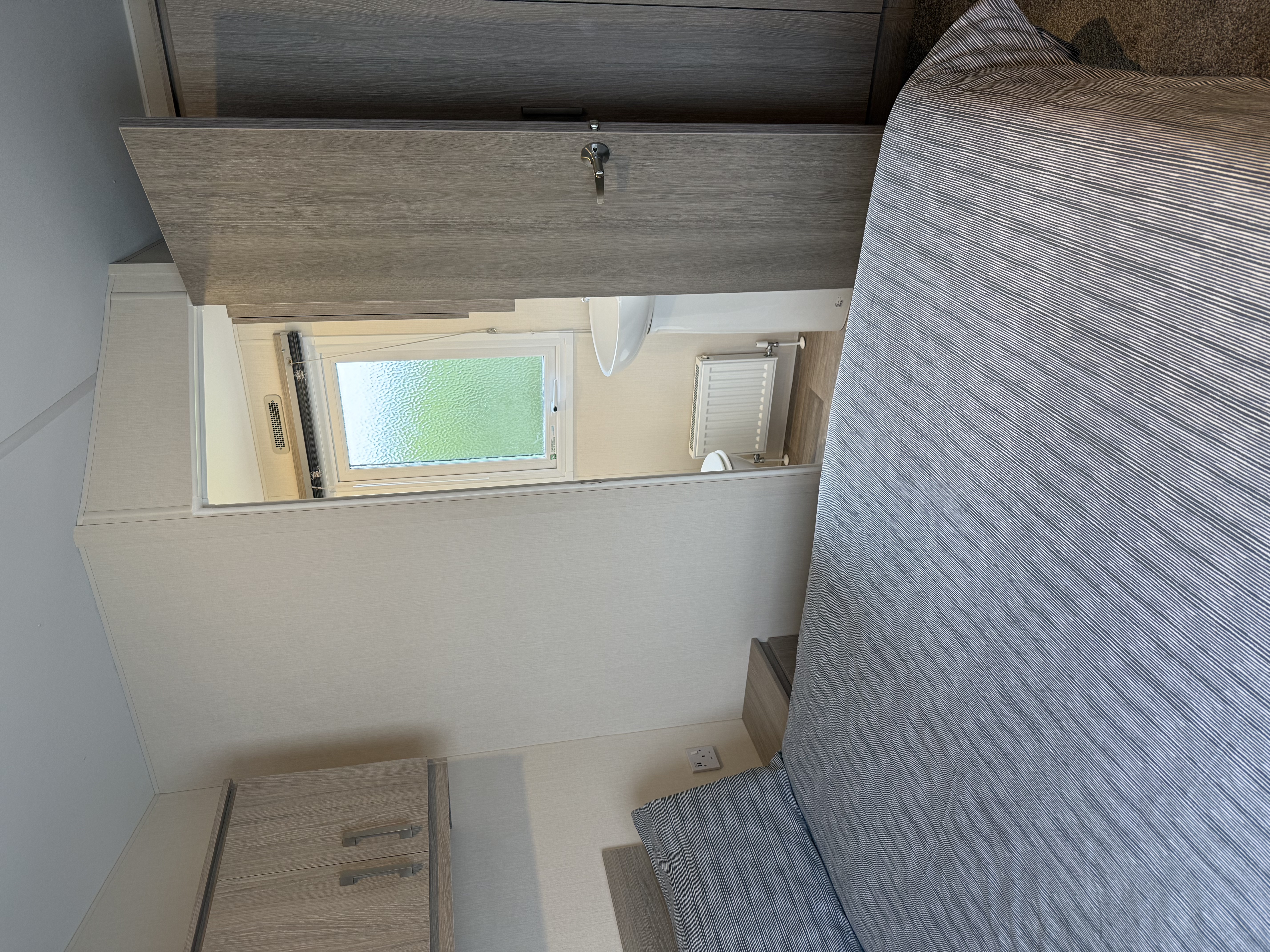 A modern bedroom with a neatly made bed and an open door revealing a small bathroom.