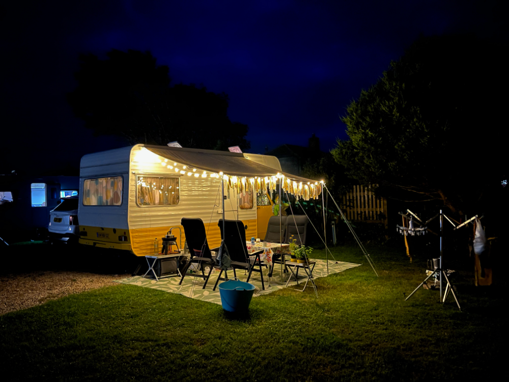 Motorhome with string lights at night in a grassy outdoor setting