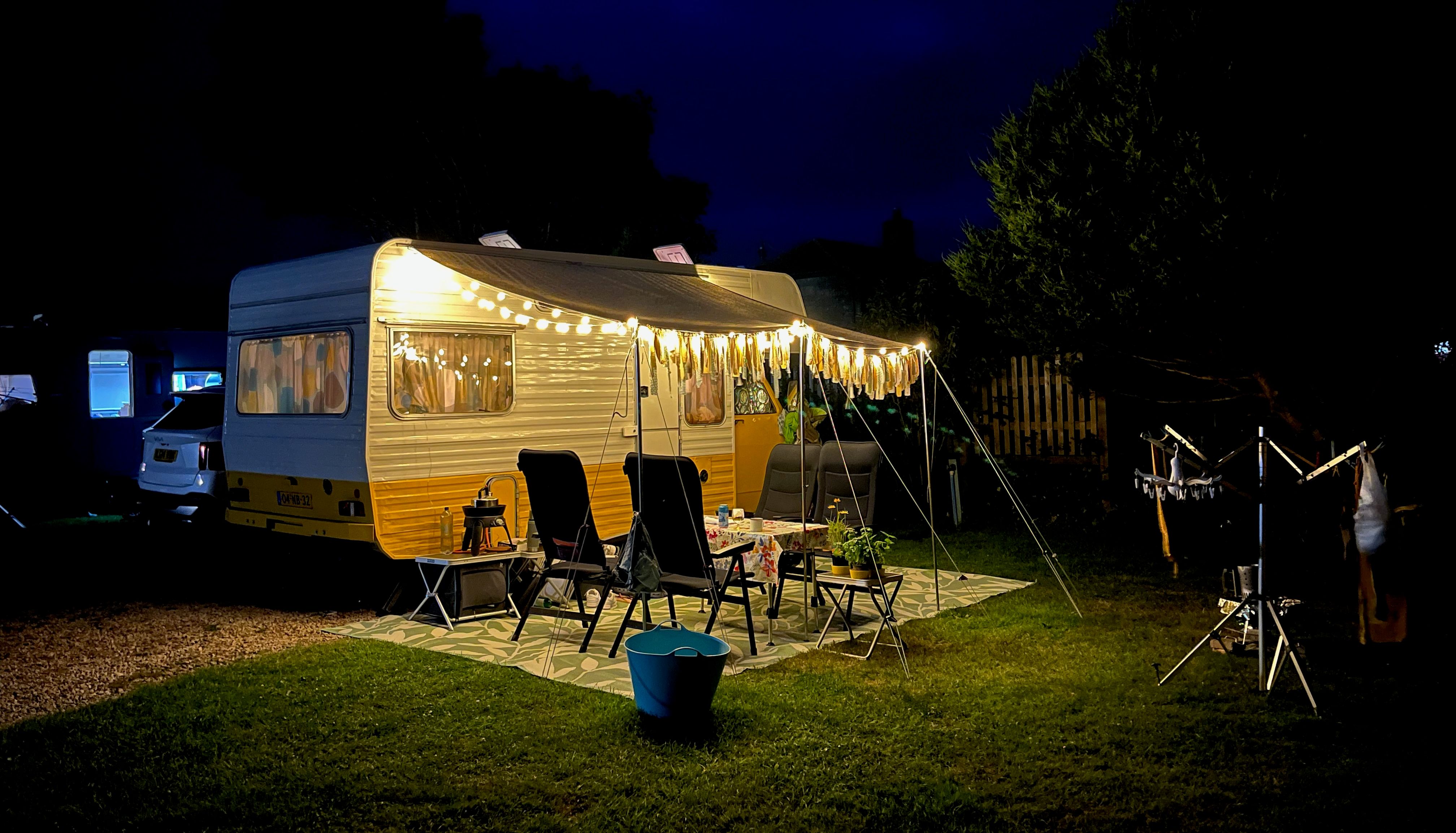 Motorhome with string lights at night in a grassy outdoor setting