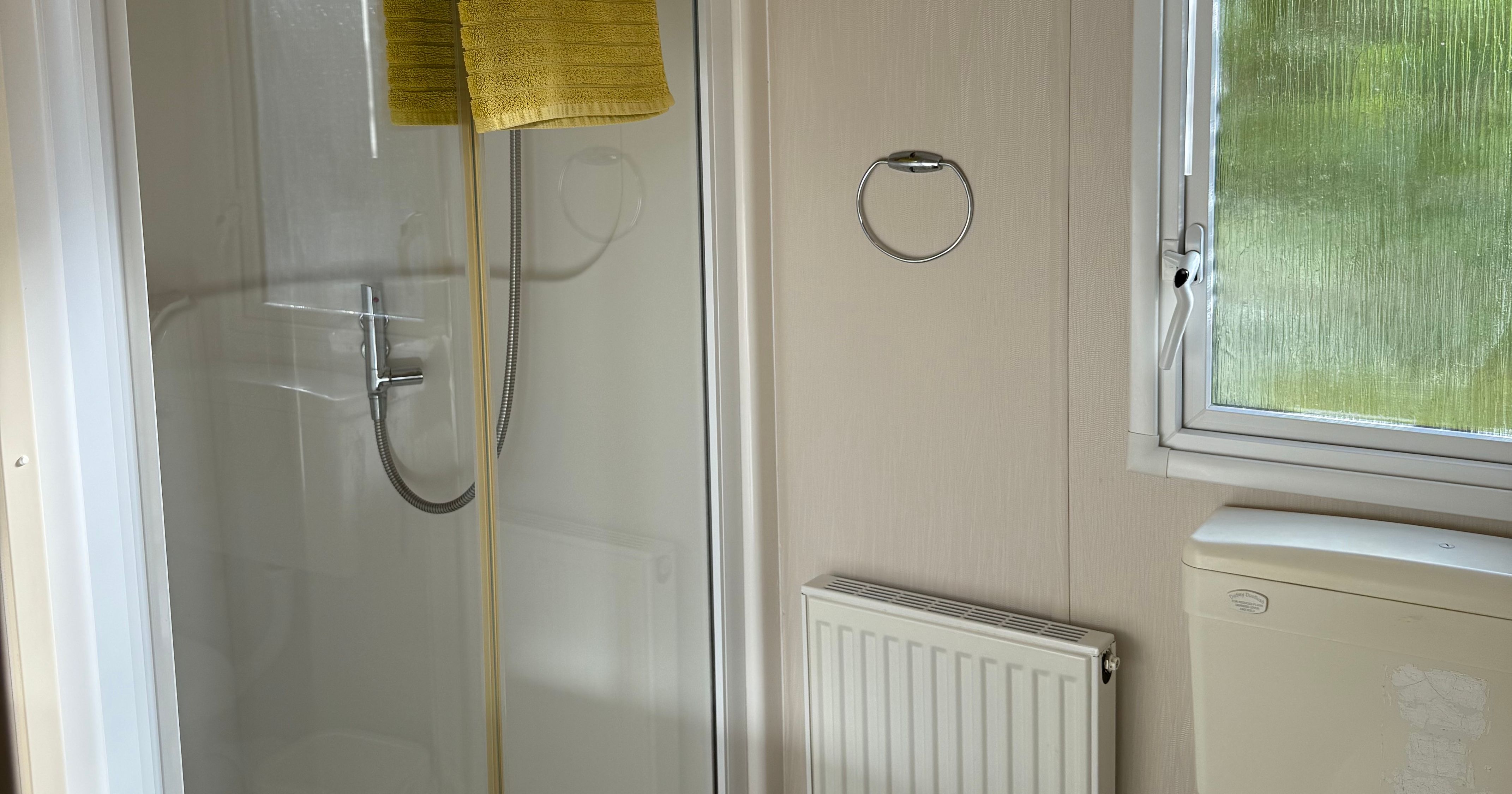 Compact bathroom with shower, toilet, towel, sink and window