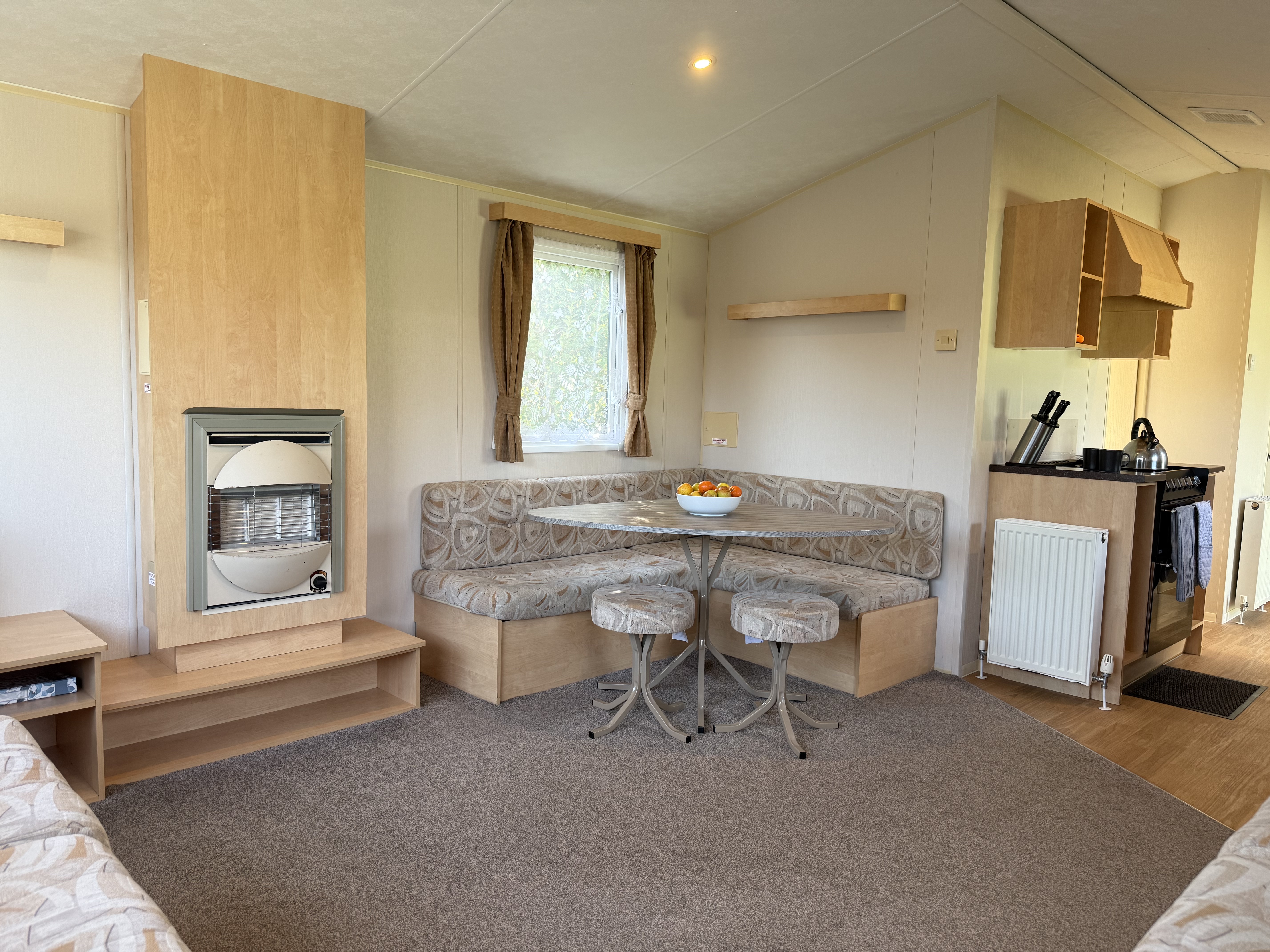 Interior of a cozy mobile home with a dining nook, heater, and kitchen area.