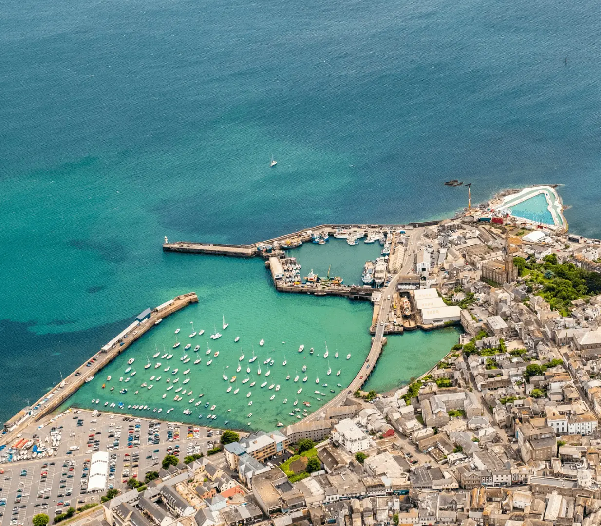 Aerial view of a coastal town with a marina, harbor, and surrounding urban area.