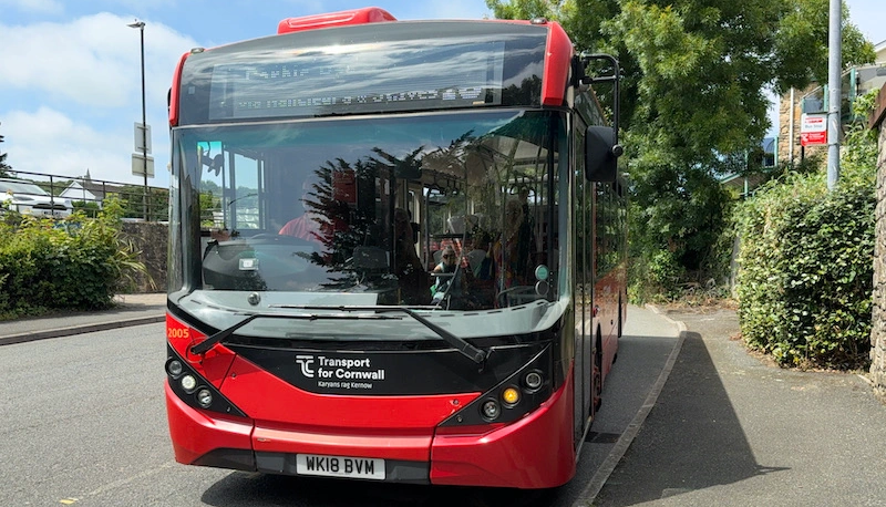 Red Transport for Cornwall bus parked at a bus stop.