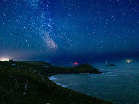 Starry night sky with the Milky Way over a coastal landscape
