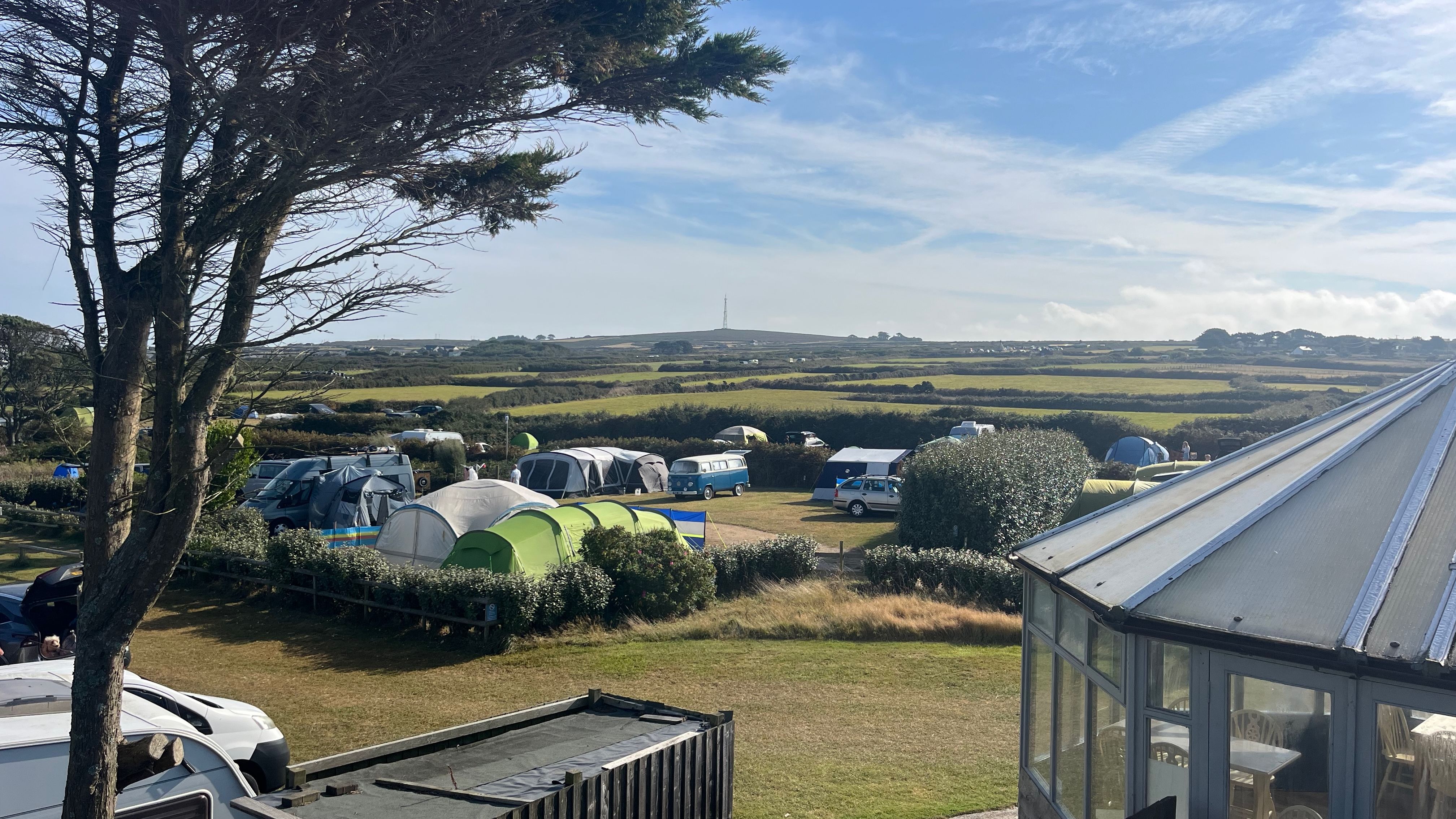 Campsite with tents and campers on grassy fields under a blue sky