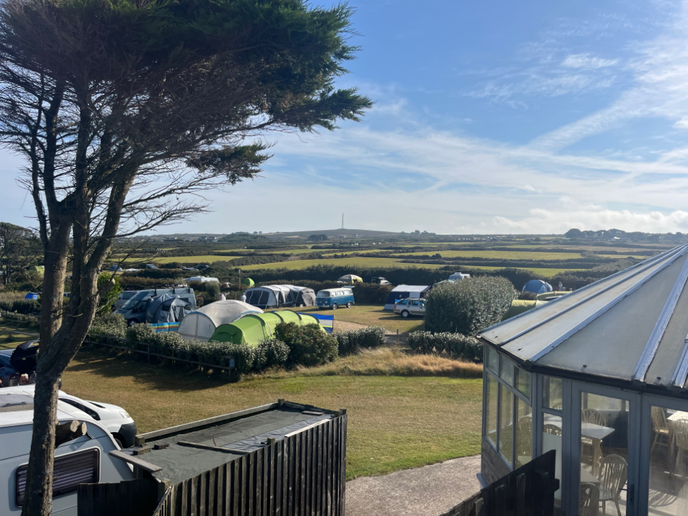 Campsite with tents and campers on grassy fields under a blue sky