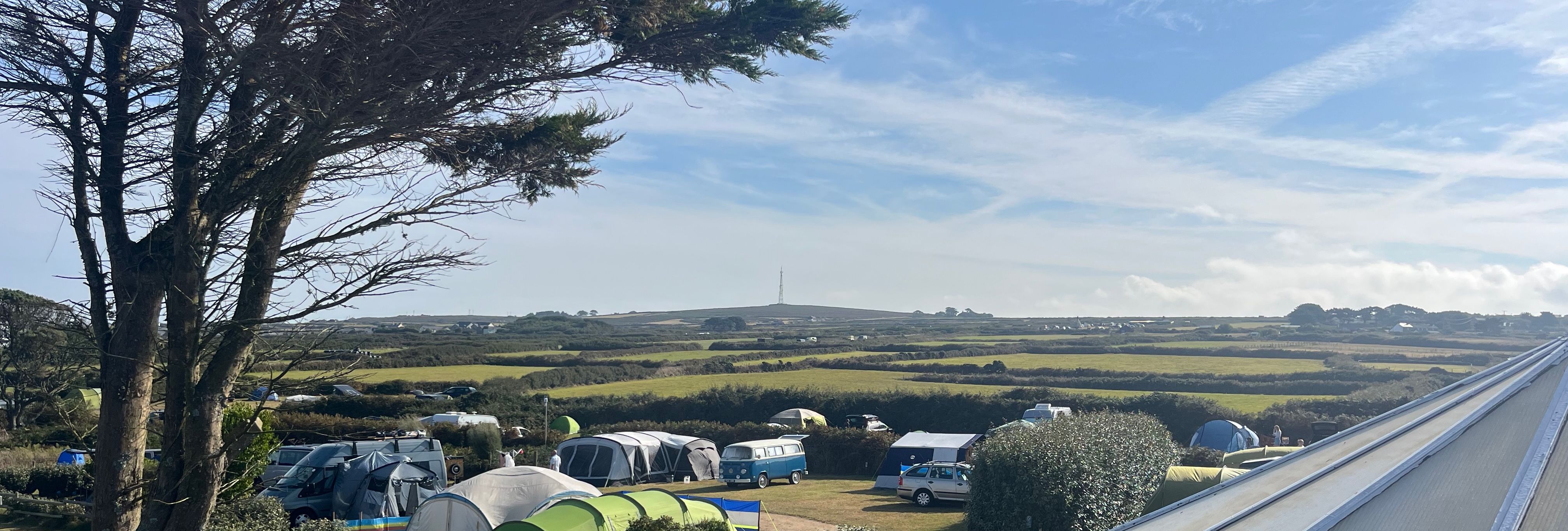 Campsite with tents and campers on grassy fields under a blue sky