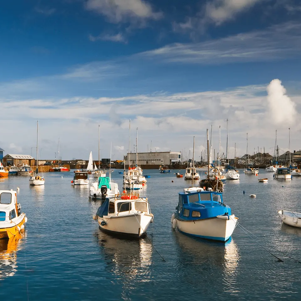 Boats docked in a harbor under a blue sky with scattered clouds