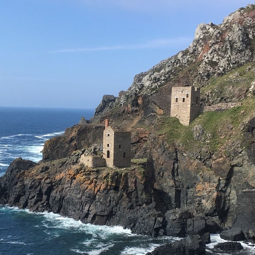 Old stone mining buildings perched on rugged cliffs above the sea