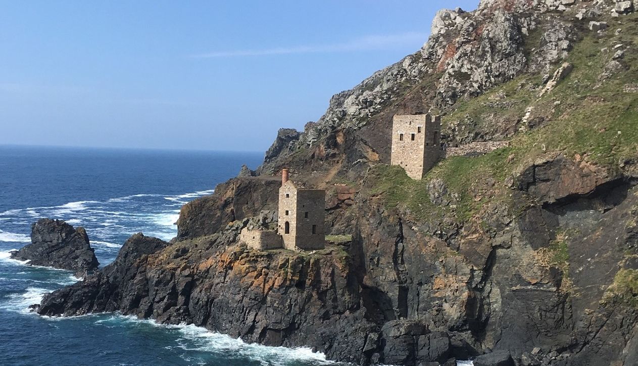 Old stone mining buildings perched on rugged cliffs above the sea