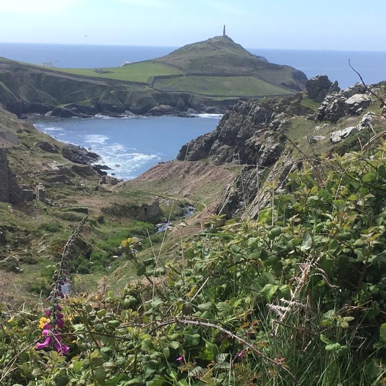 Coastal landscape with rocky cliffs, ruins, and grassy hills overlooking the ocean