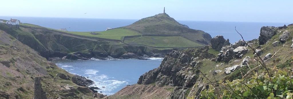 Coastal landscape with rocky cliffs, ruins, and grassy hills overlooking the ocean
