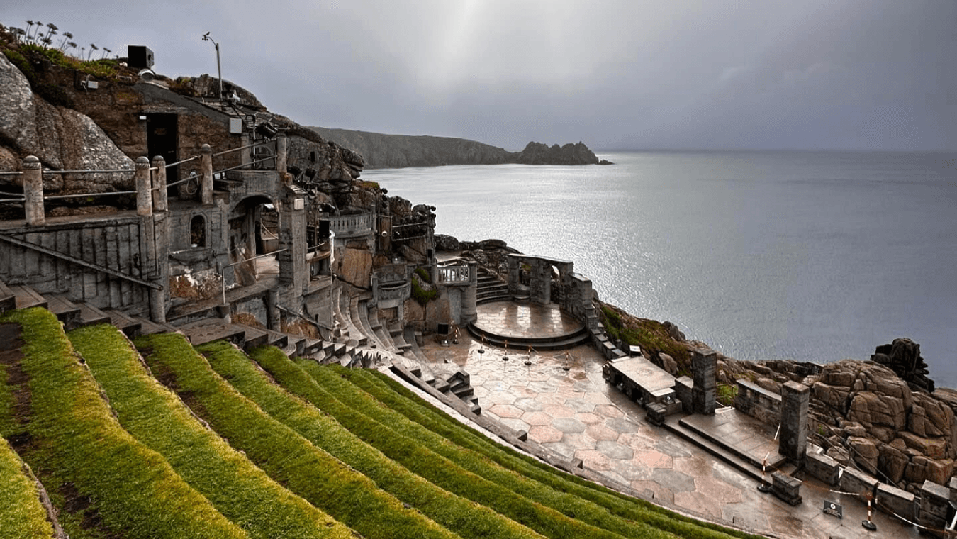 Open-air stone amphitheatre overlooking the sea with green grass terraces