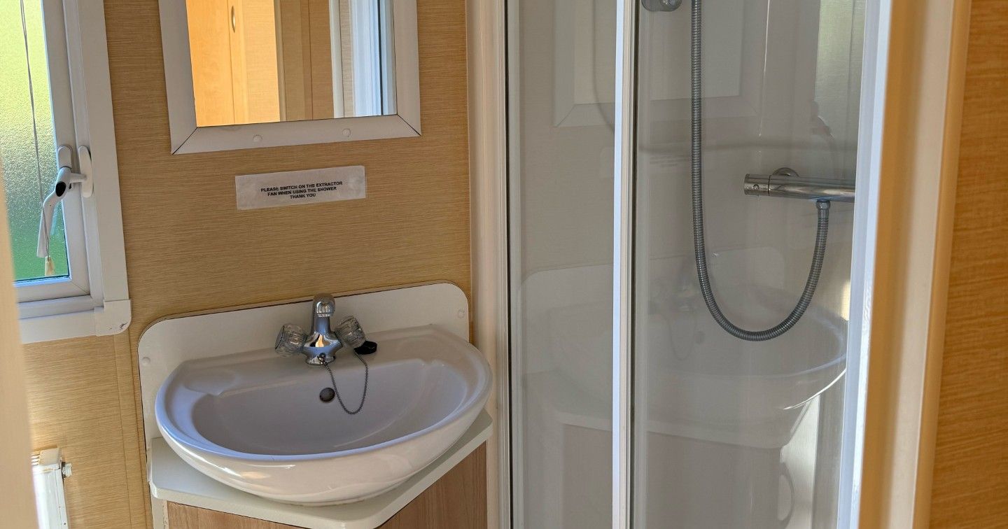 Small bathroom with a sink, mirror, and shower enclosure