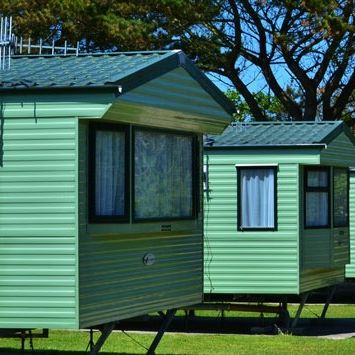 Row of green holiday caravans surrounded by trees and greenery