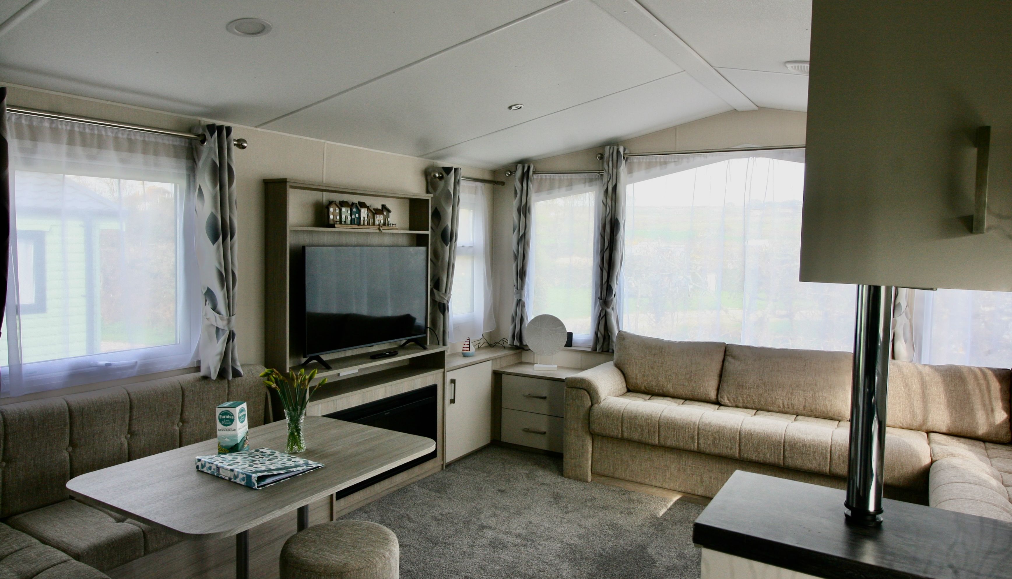 Modern living room with large windows, beige sofas, and flat screen TV