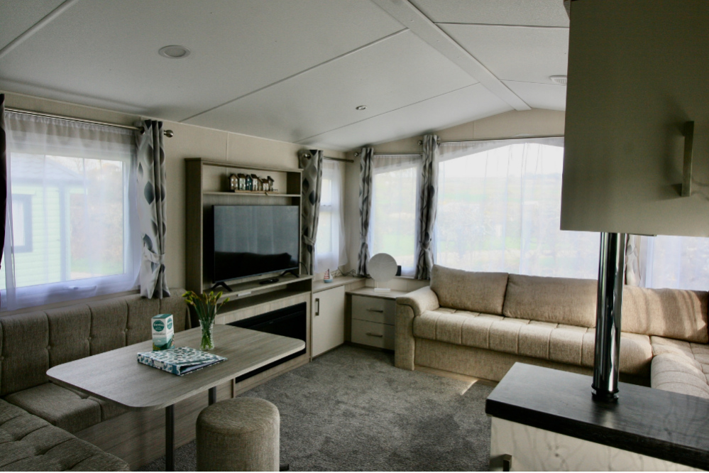 Modern living room with large windows, beige sofas, and flat screen TV