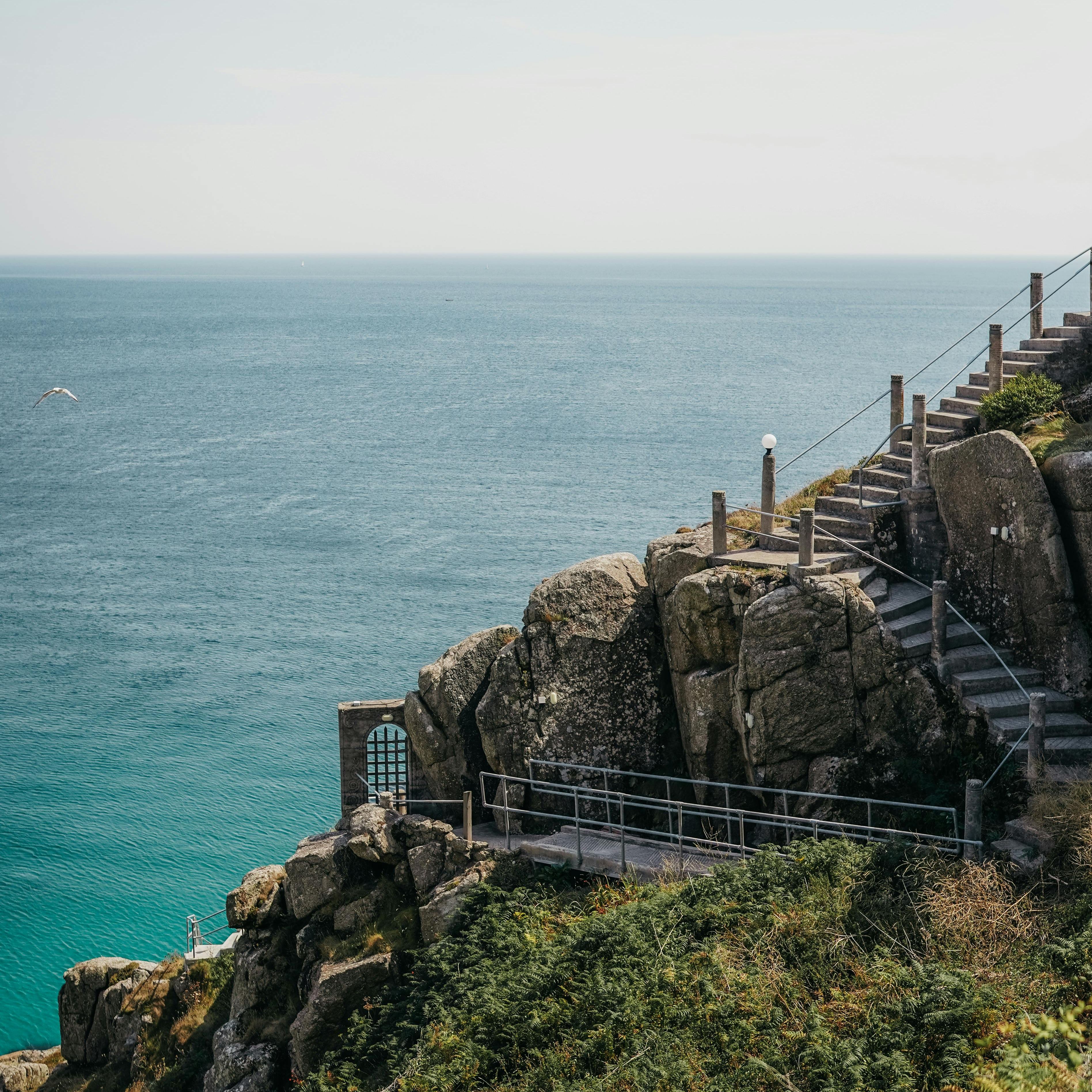 Stone steps and a pathway built along a rocky cliffside overlooking the ocean.