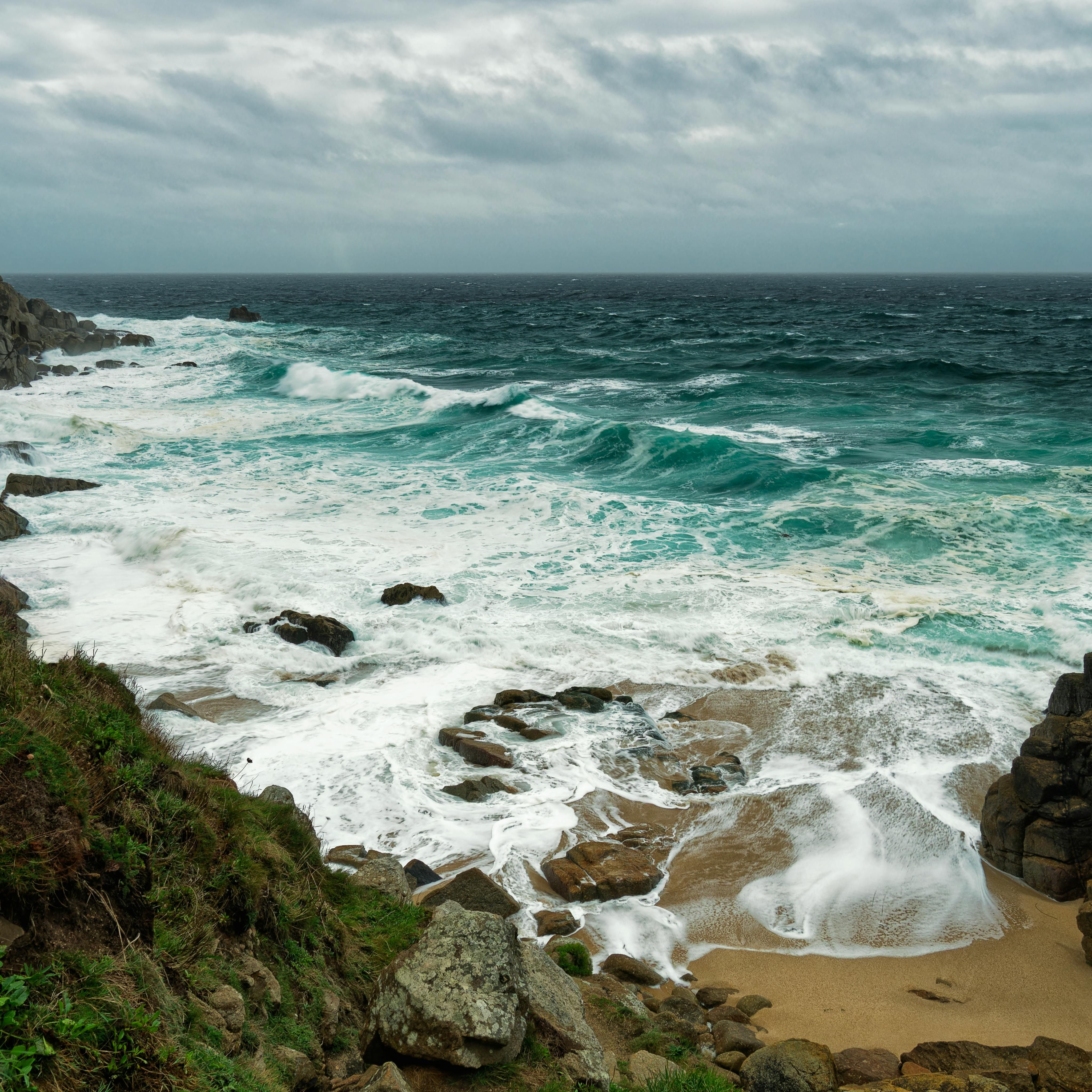 Rocky coastline with waves crashing onto the shore under a cloudy sky