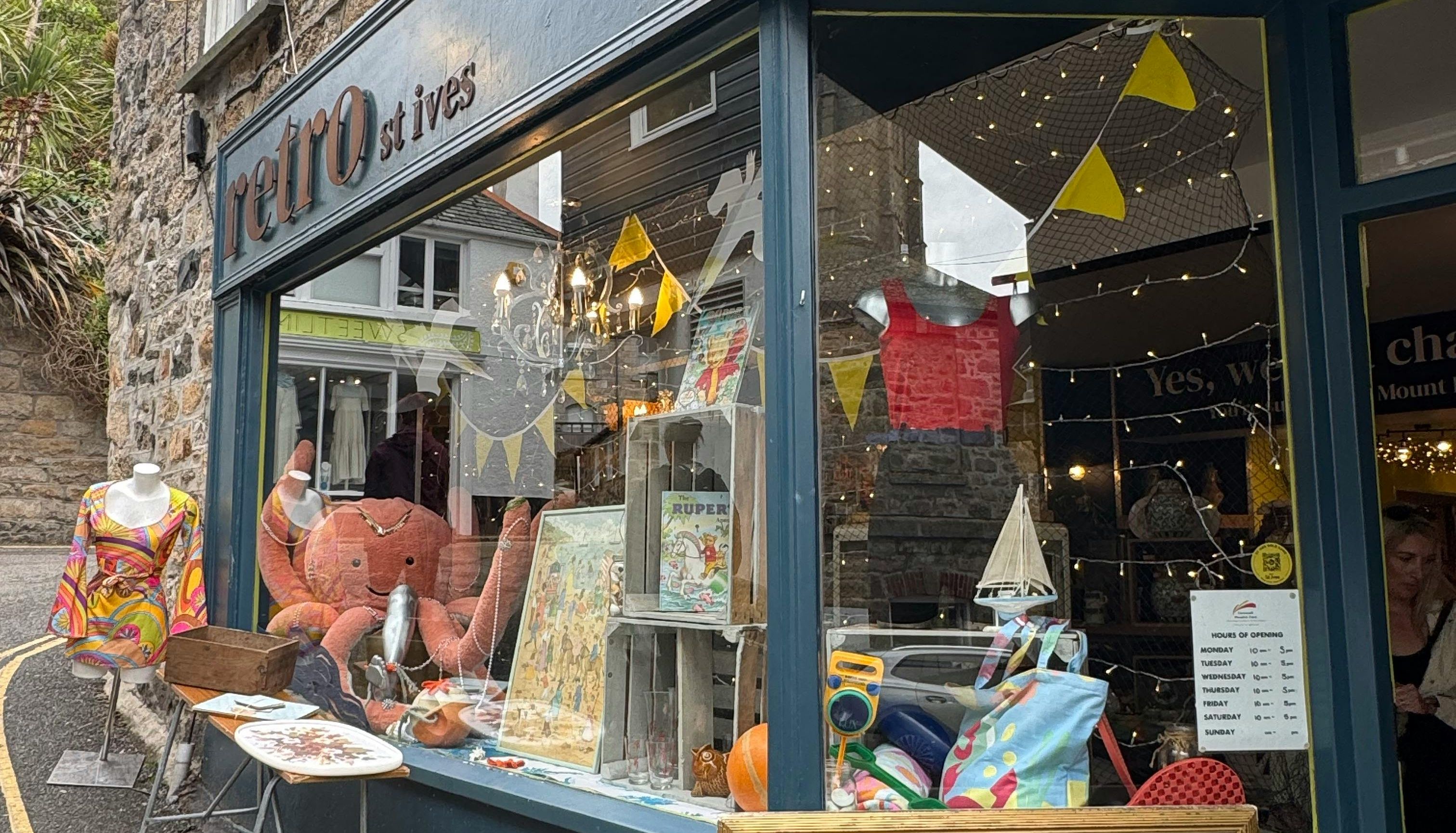 Retro store exterior in St Ives with vintage items, mannequins, and an 'OPEN' sign displayed in the window.