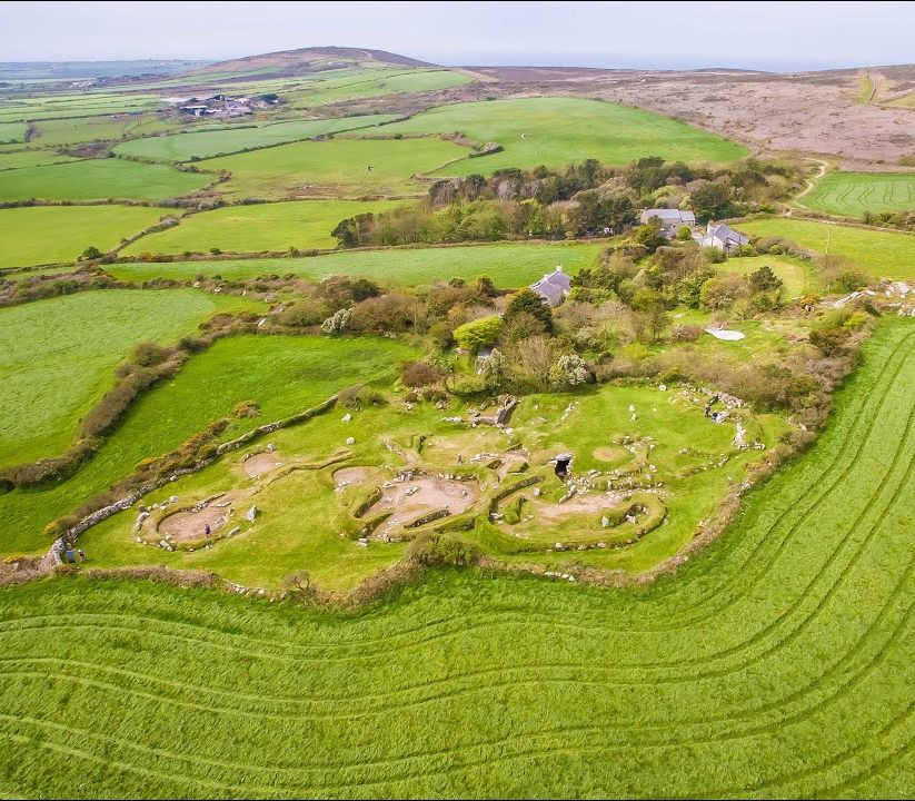 Aerial view of an ancient village ruin surrounded by green fields and farmlands