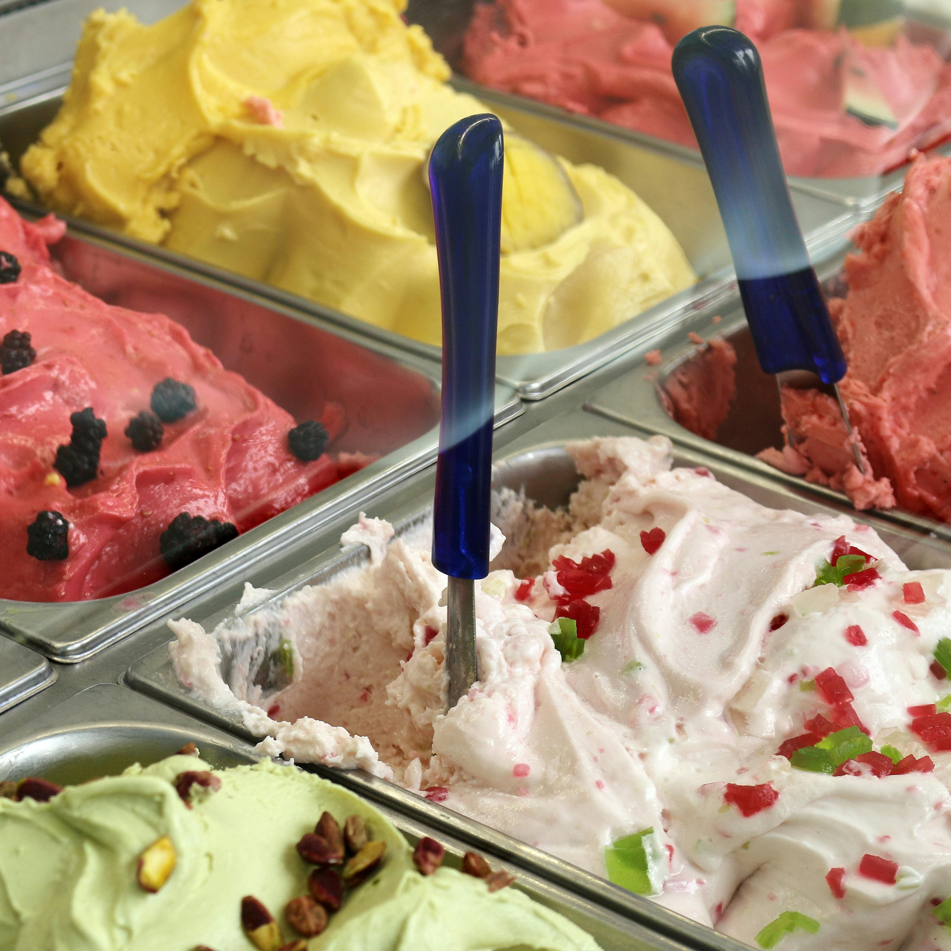 Various flavors of colorful gelato in metal containers at a shop