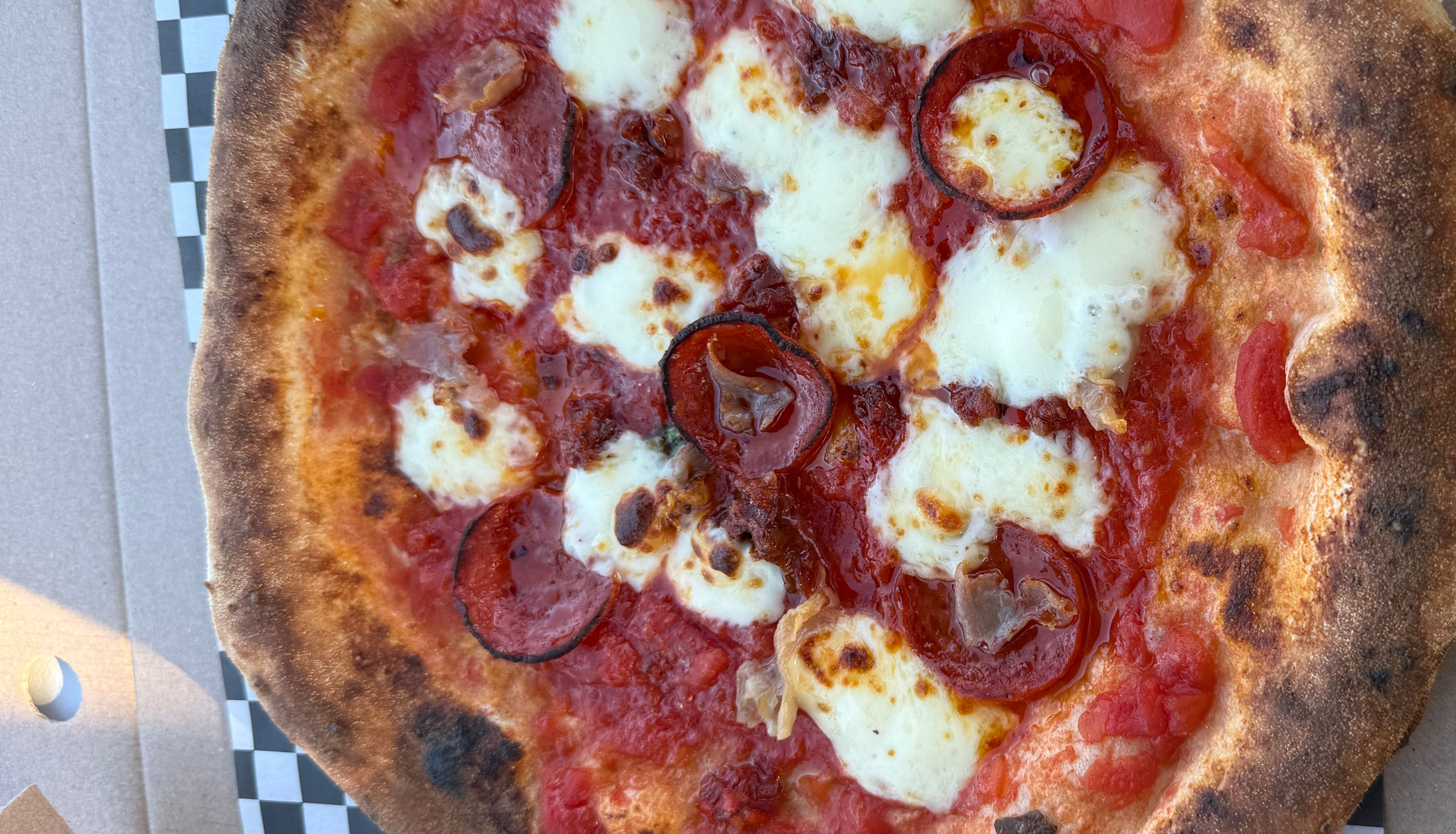 A cooked pizza with pepperoni, cheese, and tomato sauce in a pizza box